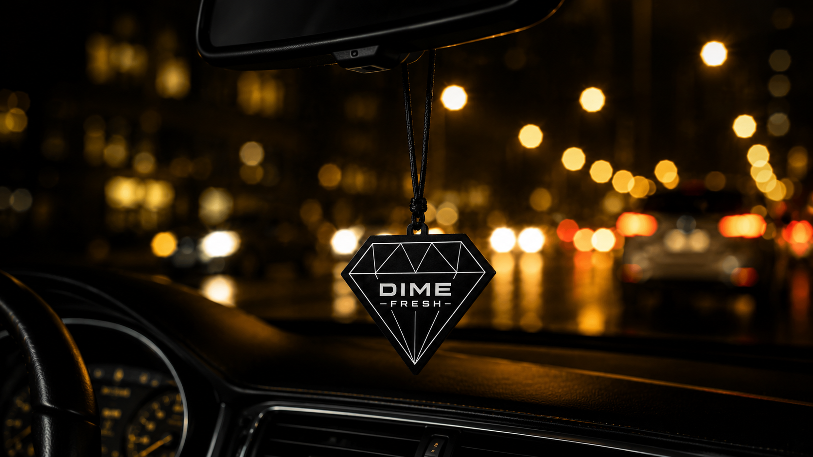 Aromatizante Dime Fresh pendurado no retrovisor de um carro à noite